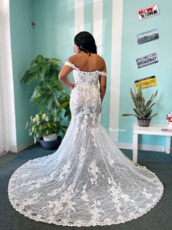 Bride showing off an off-shoulder lace gown with a long train, altered by NYC Alterations